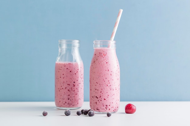 Vista frontal botellas de batido rosa con arándanos