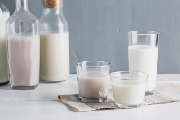 Vista frontal botellas y vasos de leche