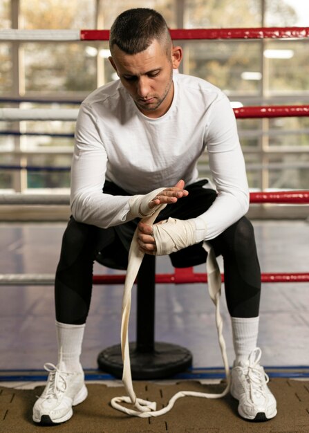 Vista frontal del boxeador masculino envolviendo sus manos antes de entrenar en el ring