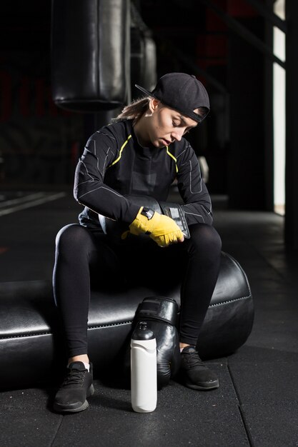 Vista frontal de la boxeadora arreglando sus guantes protectores