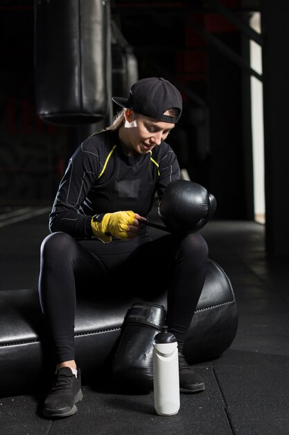 Vista frontal de la boxeadora poniéndose guantes protectores