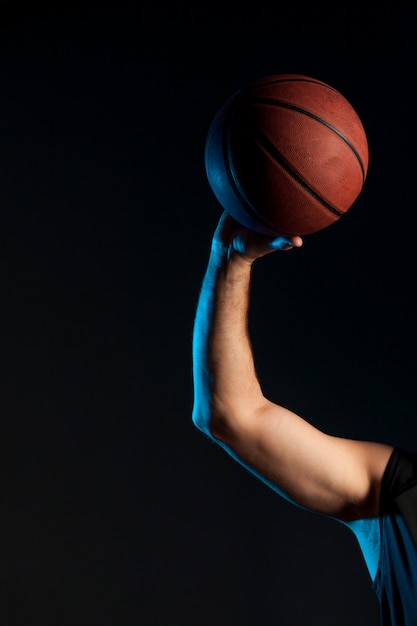 Vista frontal del brazo del jugador de baloncesto sosteniendo la pelota