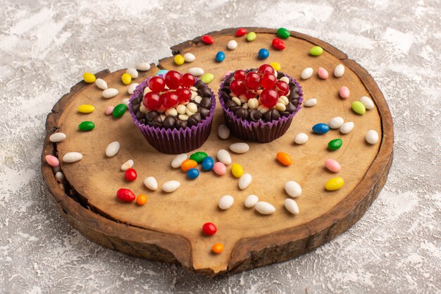 Vista frontal de brownies de chocolate con dulces en la tabla de madera