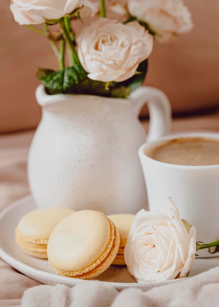 Vista frontal del café de la mañana con rosas y macarons