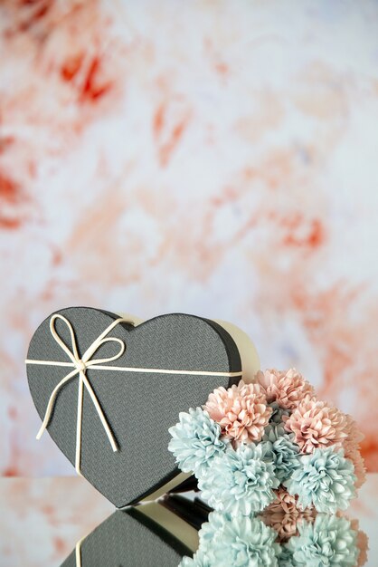 Vista frontal de la caja de corazón negro flores de colores sobre fondo beige borroso
