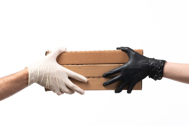 Foto gratuita una vista frontal cajas de pizza que se entregan de mujer a hombre tanto en guantes en blanco