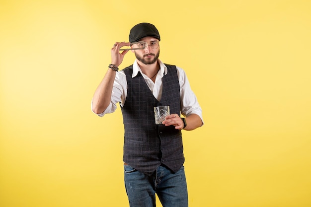 Foto gratuita vista frontal del camarero masculino haciendo bebida con cubitos de hielo en la pared amarilla beber alcohol trabajo nocturno bar club masculino