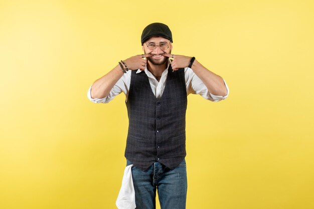 Vista frontal del camarero masculino sonriendo y posando en la pared amarilla modelo bebida trabajo trabajo club noche masculina