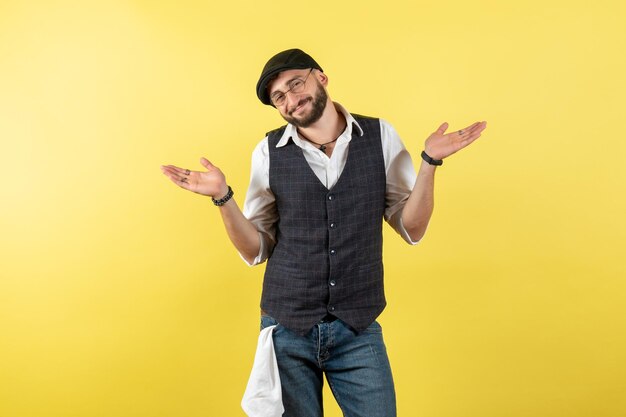 Vista frontal del camarero masculino sonriendo y posando en la pared amarilla modelo bebida trabajo trabajo club noche masculina