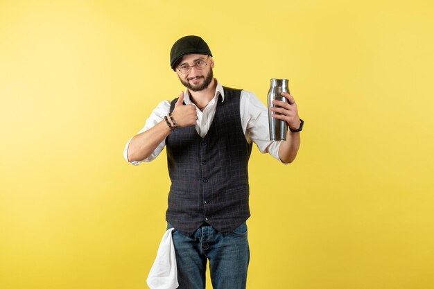 Vista frontal camarero masculino sosteniendo coctelera de plata en la pared amarilla modelo nocturno bebida trabajo club trabajo masculino