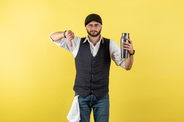 Vista frontal camarero masculino sosteniendo coctelera de plata en la pared amarilla modelo nocturno bebida trabajo club trabajo masculino