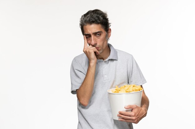 Vista frontal de la canasta de explotación masculina joven con papas fritas deprimido sobre la superficie blanca