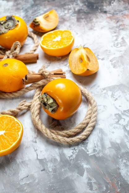 Vista frontal de los caquis frescos con naranja y canela en la mesa de luz