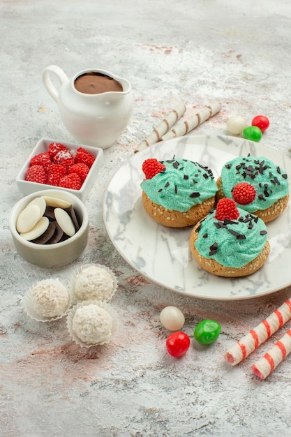 Vista frontal caramelos de colores con tortas de crema sobre fondo blanco galleta pastel dulce galleta azúcar