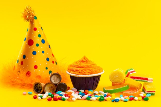 Una vista frontal de caramelos coloridos con mermelada y gorro de cumpleaños en amarillo, color de celebración de cumpleaños