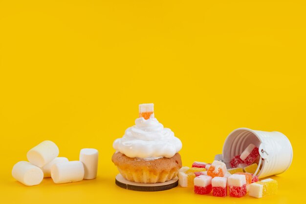 Una vista frontal de caramelos y malvaviscos con pastelito amarillo, bizcocho de azúcar dulce