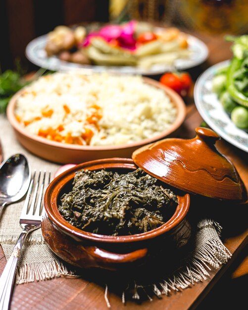 Vista frontal de carne al horno con verduras en una olla con arroz hervido