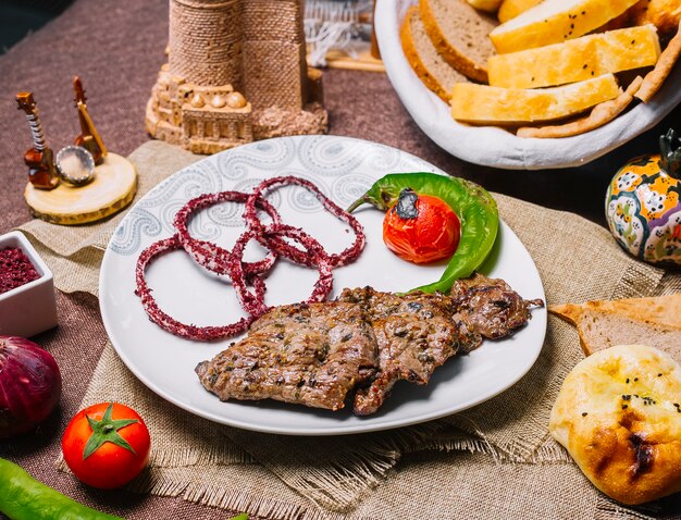 Vista frontal carne basturma kebab con tomate y pimiento picante a la parrilla con cebolla en zumaque