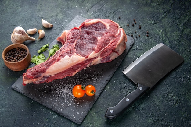 Vista frontal de la carne grande rebanada de carne cruda con pimienta en la comida de animal oscura foto de carnicero comida de pollo barbacoa