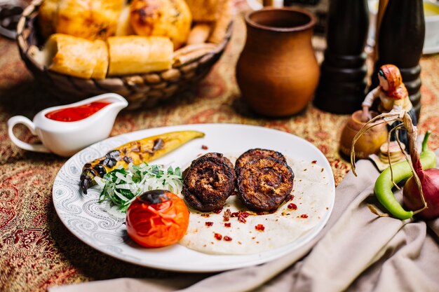 Vista frontal de carne a la parrilla sobre pan de pita con tomate y cebolla