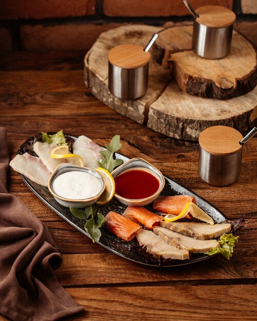 Una vista frontal de carne y pescado con diferentes salsas en la mesa de madera comida comida carne