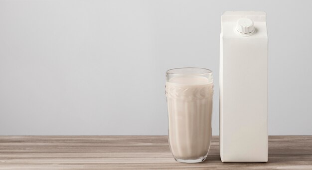Vista frontal del cartón de leche con vaso lleno y espacio de copia