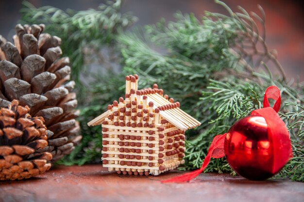 Vista frontal de la casa de fósforos árbol de navidad bola de juguete rama de árbol de pino con piña año nuevo