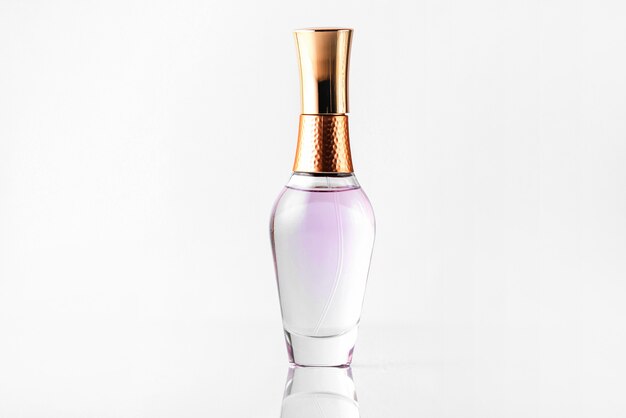Una vista frontal de cerca botella de perfume transparente y bronce aislado en el piso blanco