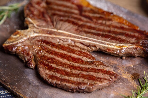 Vista frontal cercana carne a la parrilla frita sabrosa en el mostrador de madera con hierbas