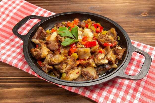 Vista frontal cercana comida vegetal cocida que incluye verduras y carne dentro de un escritorio marrón de madera