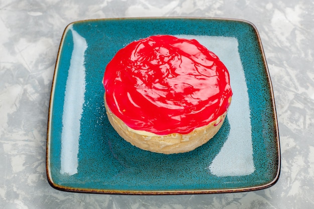 Vista frontal cercana deliciosa tarta de pastel con crema roja sobre la superficie blanca