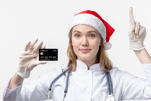 Vista frontal cercana de la doctora sosteniendo una tarjeta bancaria en la pared blanca