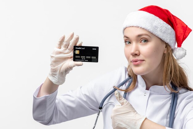 Vista frontal cercana de la doctora sosteniendo una tarjeta bancaria en la pared blanca