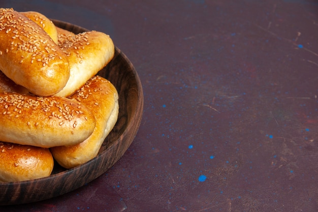 Vista frontal cercana empanadas dulces deliciosa masa horneada para té en el espacio oscuro