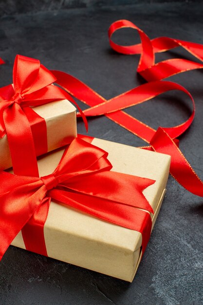 Vista frontal cercana de hermosos regalos con cinta roja sobre fondo oscuro