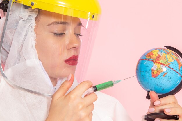 Vista frontal cercana joven hermosa mujer en traje blanco especial con casco protector globo de inyección en rosa