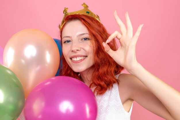 Vista frontal cercana joven mujer sosteniendo globos de colores en la rosa