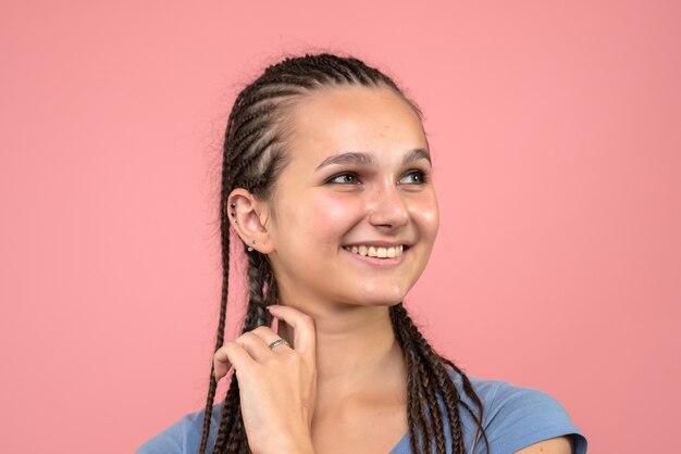 Vista frontal cercana de la joven sonriendo felizmente en rosa claro