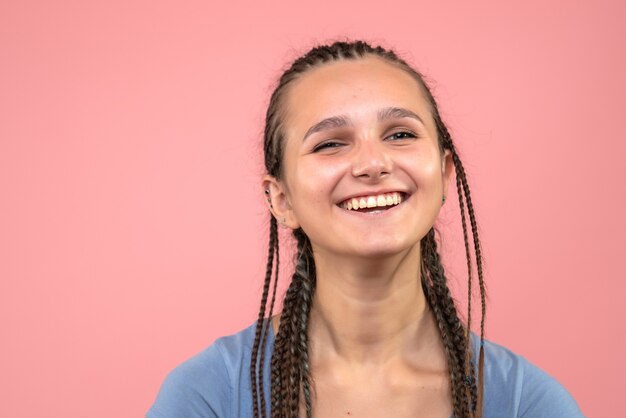 Vista frontal cercana de la joven sonriendo felizmente en rosa