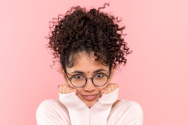 Vista frontal cercana de la mujer joven sonriendo en rosa