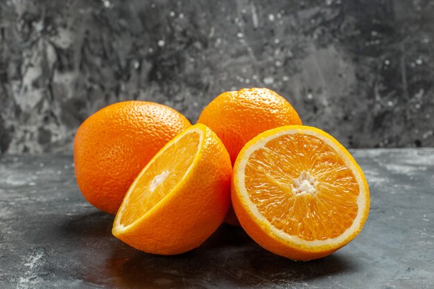 Vista frontal cercana de naranjas frescas orgánicas naturales enteras y cortadas alineadas en dos filas sobre fondo oscuro