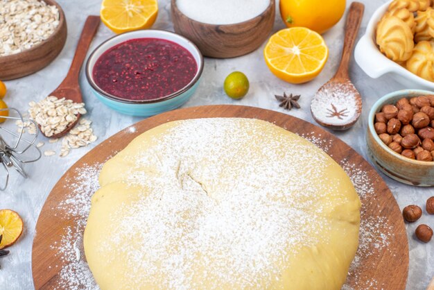 Vista frontal cercana de pastelería cruda en tablero redondo y conjunto de varios ralladores de alimentos sobre fondo de hielo