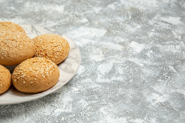 Vista frontal cercana poco postre delicioso de las galletas suaves para el té dentro de la placa en la superficie blanca pastel de galletas hornear galletas dulces de azúcar