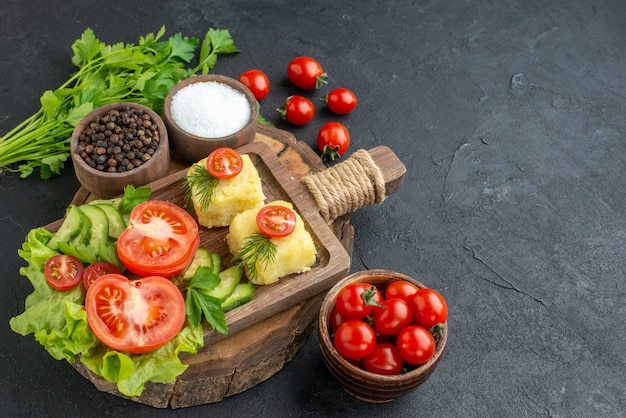 Vista frontal cercana de queso de verduras frescas picadas en la tabla de cortar y el paquete verde de especias sobre superficie negra