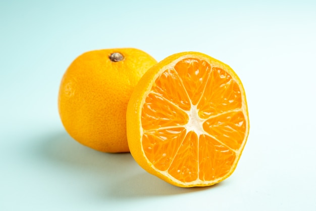 Vista frontal cercana rodajas de mandarina fresca en mesa azul claro