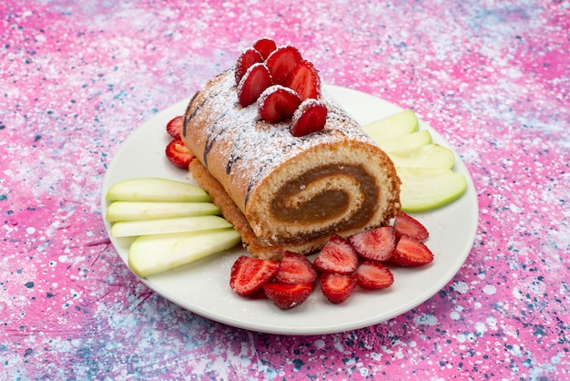 Vista frontal cercana roll cake con frutas dentro de un plato blanco sobre la superficie coloreada