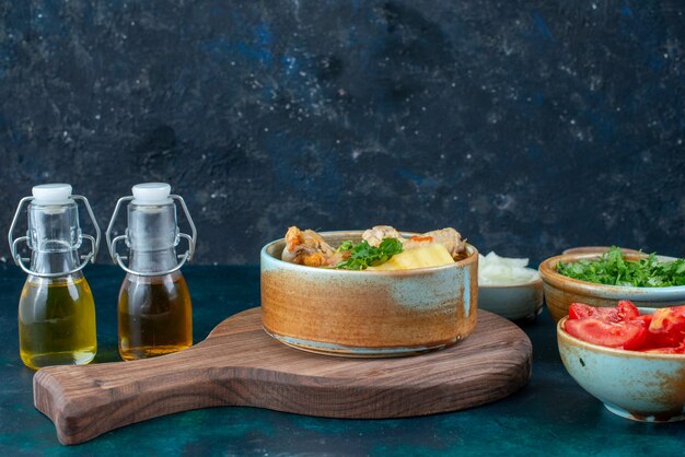 Vista frontal cercana sopa de pollo con patatas junto con sal, pimienta, verduras frescas y aceite en el escritorio azul oscuro sopa carne comida comida