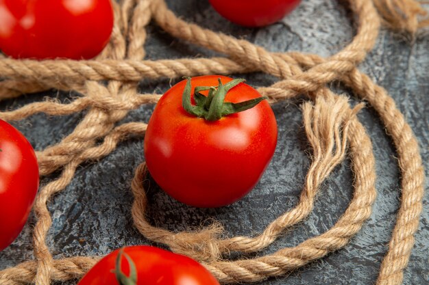 Vista frontal cercana tomates rojos frescos con cuerdas
