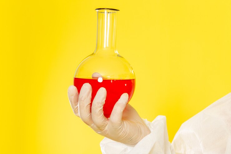 Foto gratuito vista frontal cercana trabajador científico masculino en traje de protección especial sosteniendo el matraz con solución roja en el escritorio amarillo