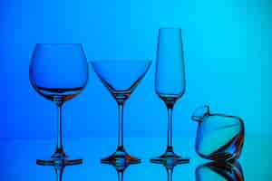 Foto gratuita vista frontal cercana de varios tipos de copa de vidrio vacía de pie sobre la superficie azul